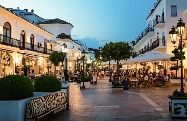 Vibrant evening scene in Torre de la Horadada with bustling cafes and shops, lively outdoor seating, and beautiful architecture."