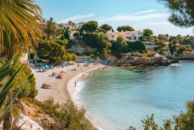 Scenic beach with turquoise water, sunbathers, and seaside villas in Spain | SunnyCasas