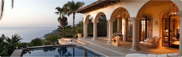 Stunning villa with ocean views, featuring elegant arches, a serene pool, and beautiful outdoor seating amidst tropical landscaping.